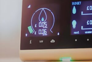 Close-up of a digital smart meter display showing real-time energy costs in British pounds and gas usage icons.