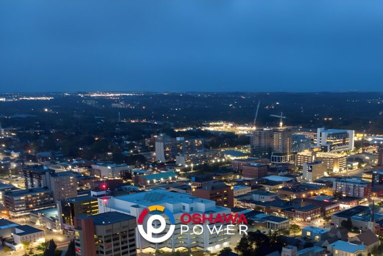 Aerial drone view of a city skyline at night with an Oshawa Power logo overlay.
