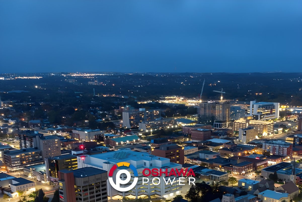 Aerial drone view of a city skyline at night with an Oshawa Power logo overlay.