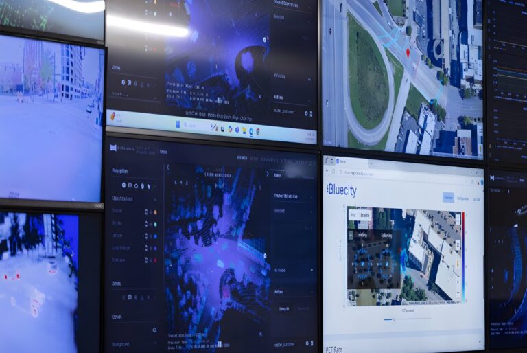 A wall of monitors displaying Bluecity lidar traffic analytics, aerial maps, and thermal intersection data.