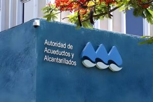 PRASA logo and "Autoridad de Acueductos y Alcantarillados" signage on a blue textured building wall under a flowering tree.