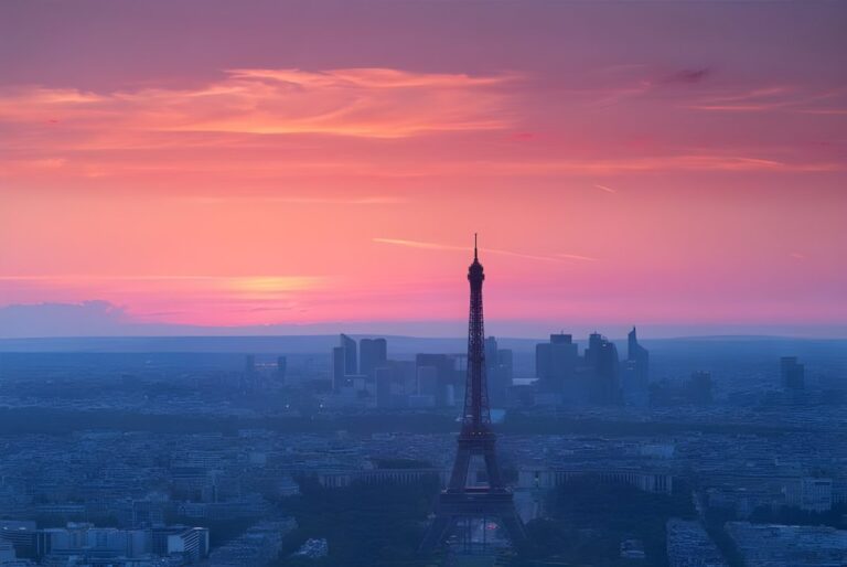 Wide aerial view of the Paris skyline and Eiffel Tower at sunset with a pink and purple sky.