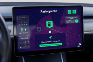 A Parkopedia navigation interface on a vehicle dashboard display showing EV charging and parking locations on a map.