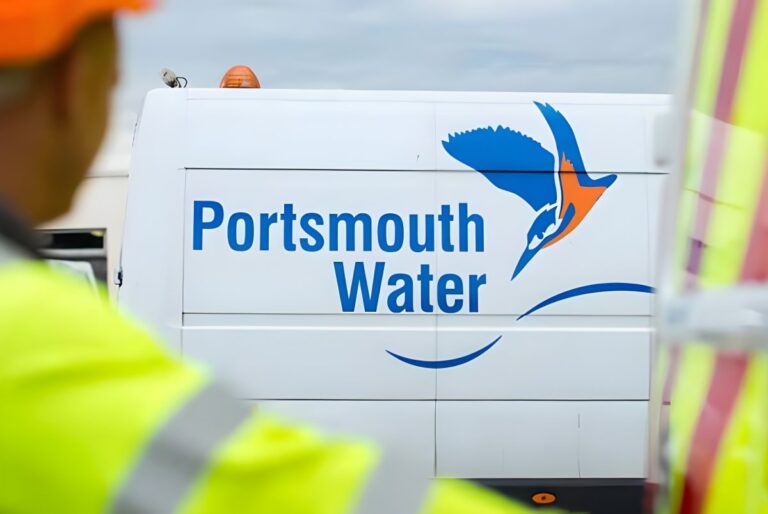 Portsmouth Water logo and kingfisher graphic on the side of a white utility van behind a worker in high-visibility gear.