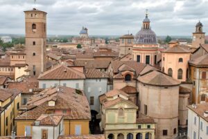 High-angle view of the historic city center of Reggio Emilia featuring terracotta rooftops, towers, and church domes.