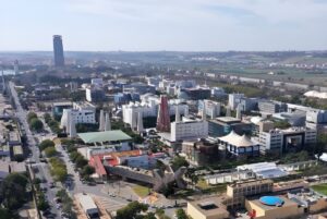 Aerial view of the Sevilla TechPark campus featuring modern office buildings, paved roads, and the Seville skyline.
