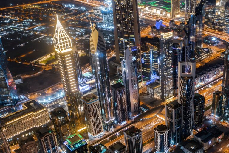 Aerial night view of illuminated skyscrapers and highway traffic in downtown Dubai.