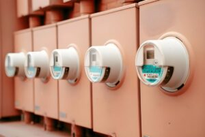 Row of digital smart electricity meters mounted on tan utility boxes.