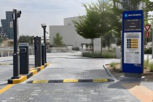 Parkonic automated parking barriers and a blue digital paid parking sign at a paved entrance in Dubai.