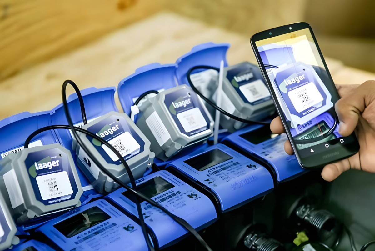 A person uses a smartphone to scan a QR code on a row of blue Laager IoT smart water meters.