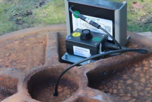 SmartCover Systems monitoring sensors and communication hardware mounted on a rusted metal manhole cover.