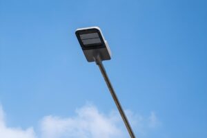 Low-angle view of a modern rectangular LED street lamp on a metal pole against a blue sky with light clouds.