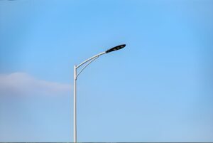 Modern LED street light fixture on a white curved pole against a clear blue sky.