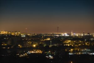 Nighttime aerial view of a Spanish city skyline illuminated by golden street lighting and building lights.