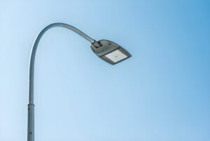 Low-angle view of a modern LED street light on a curved metal pole against a clear blue sky.