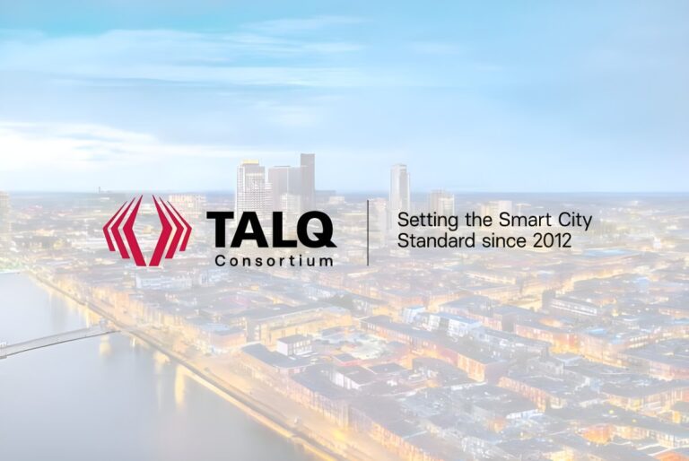 TALQ Consortium logo and slogan overlaid on a blurred aerial view of a city skyline at dusk with illuminated streets.