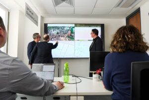 Three people review digital maps and data on a large screen at the SUEZ UK Smart Operations Centre.