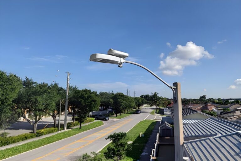 Ubicquia smart city sensor and AI camera mounted on a street light overlooking a suburban road.