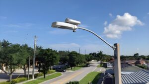 An Ubicquia UbiCell smart streetlight controller and camera mounted on a street lamp over a residential road.