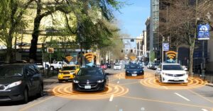 Cars driving on a city street with orange digital overlays representing connected vehicle sensors and Wi-Fi signals.