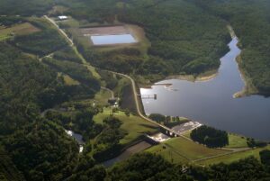 Aerial view of a water reservoir and treatment facility surrounded by dense forest.
