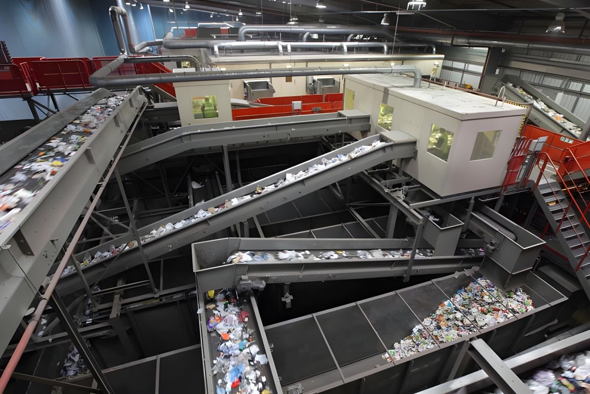 Automated conveyor belts transporting plastic waste and recyclables through a large industrial sorting facility.