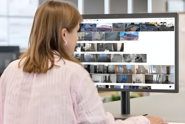 A woman views a Verkada software dashboard displaying multiple live security camera feeds on a desktop monitor.