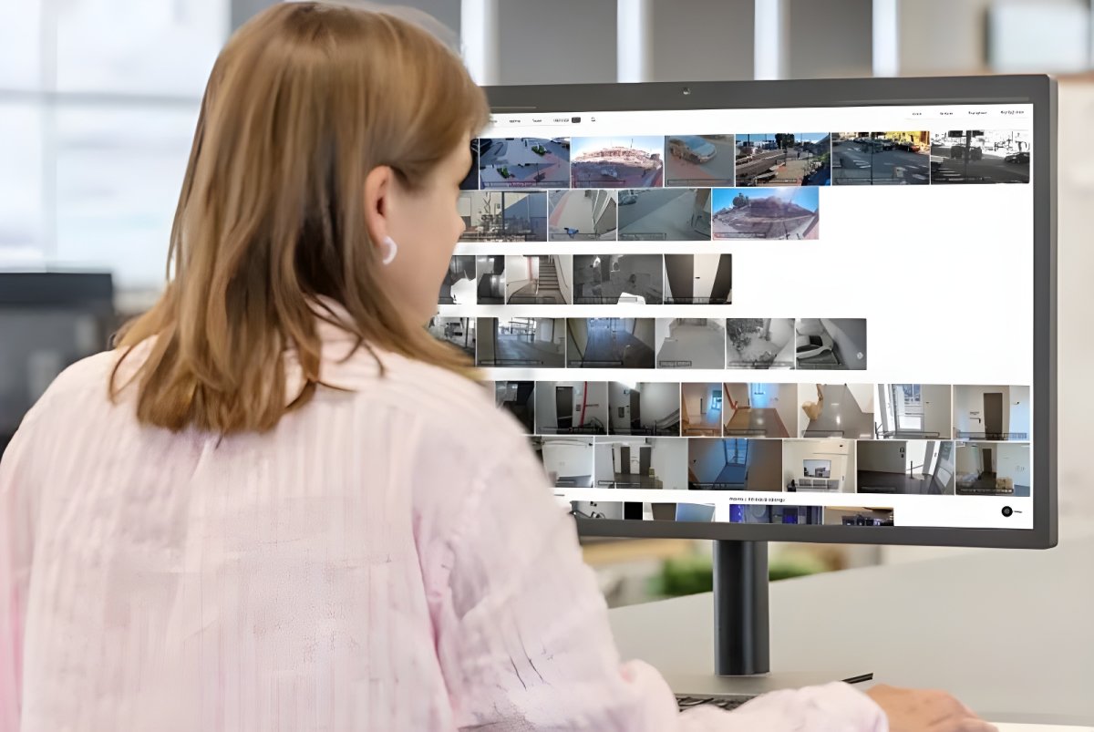 A woman views a Verkada software dashboard displaying multiple live security camera feeds on a desktop monitor.