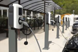 Row of white electric vehicle charging stations installed under a covered outdoor canopy.