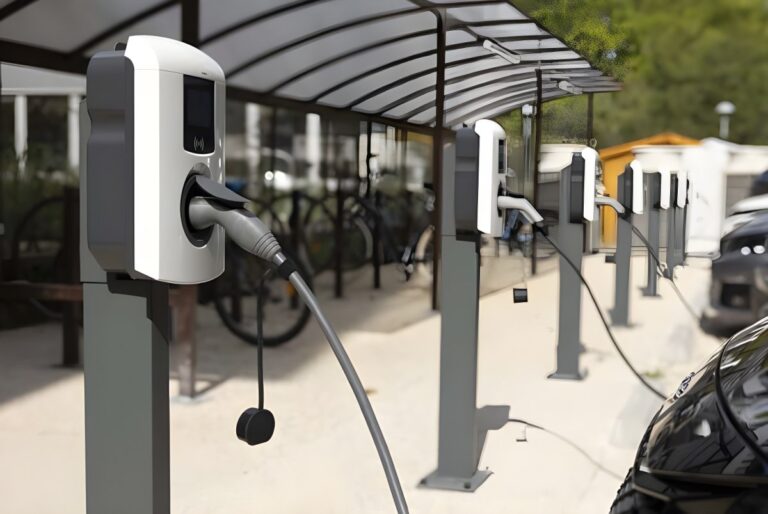 Row of white electric vehicle charging stations installed under a covered outdoor canopy.