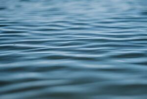 Close-up of gentle blue ripples on the surface of a body of water.