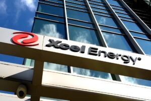Xcel Energy logo and signage on the exterior of a glass office building under a blue sky.