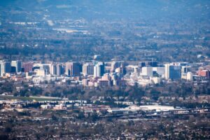 High-angle aerial view of the San Jose city skyline and surrounding suburban landscape.