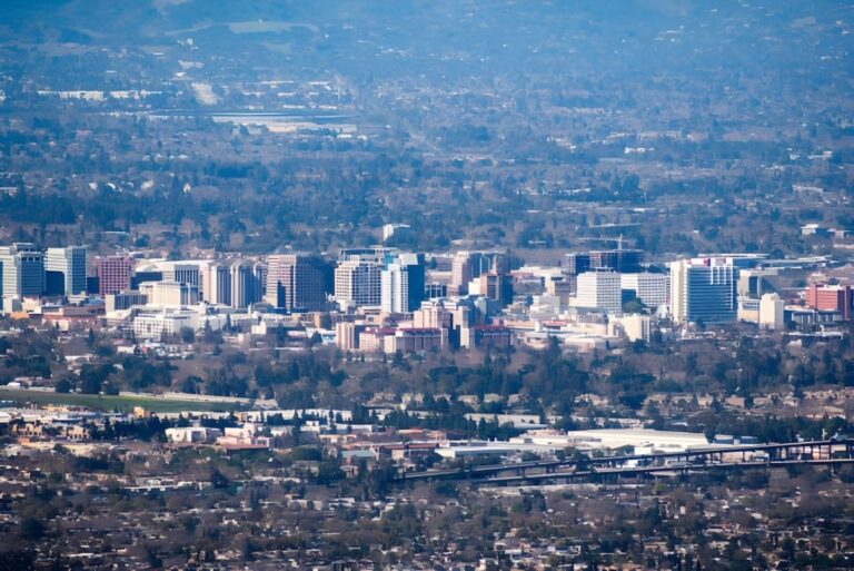 High-angle aerial view of the San Jose city skyline and surrounding suburban landscape.