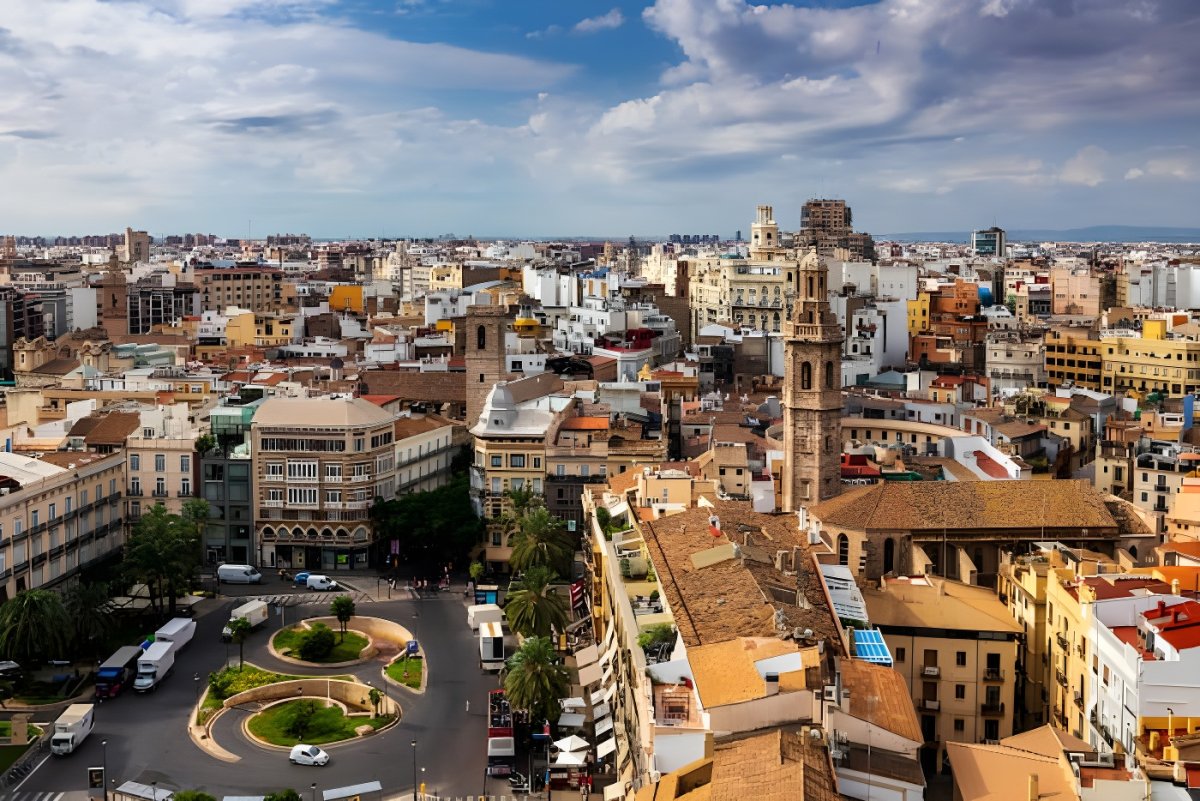 High-angle cityscape of Valencia, Spain, featuring historic architecture, church steeples, and a street-level roundabout.