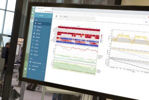 Computer monitor displaying the etalytics software dashboard with energy data heatmaps and line graphs.