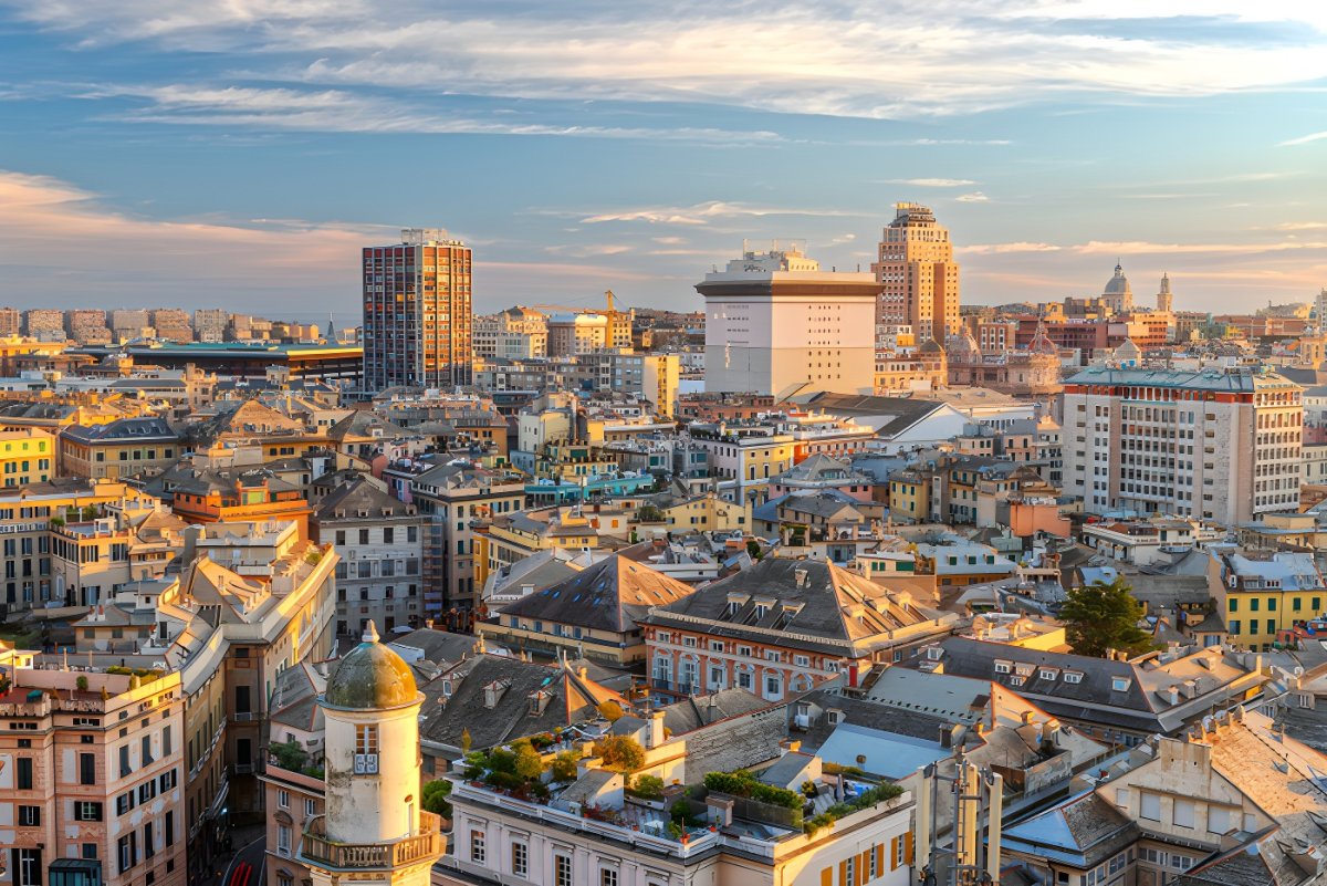 Elevated view of the Genoa city skyline featuring historic architecture and modern high-rise buildings at sunset.