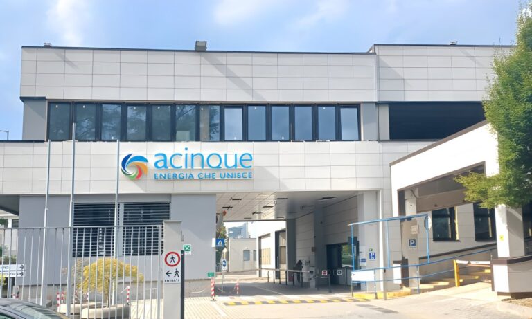 Exterior view of an Acinque office building with a gated entrance and company signage on the facade.
