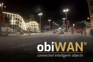 Nighttime city street with illuminated smart lighting poles and an obiWAN logo overlay.