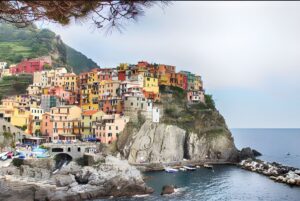 Colorful buildings of Manarola village clustered on a rocky cliff overlooking the Ligurian Sea in Cinque Terre, Italy.