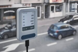 A Telraam S2 traffic counting sensor mounted on a window overlooking a city street with blurred cars.